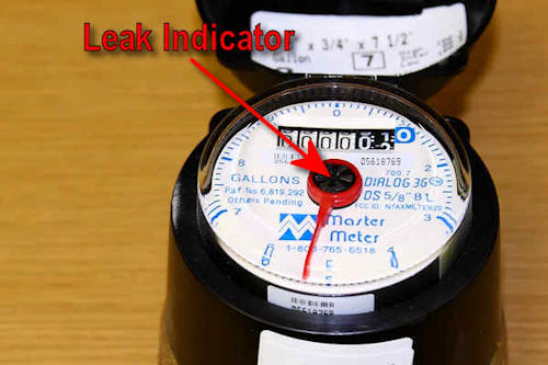 Close-up of water meter showing the leak indicator dial